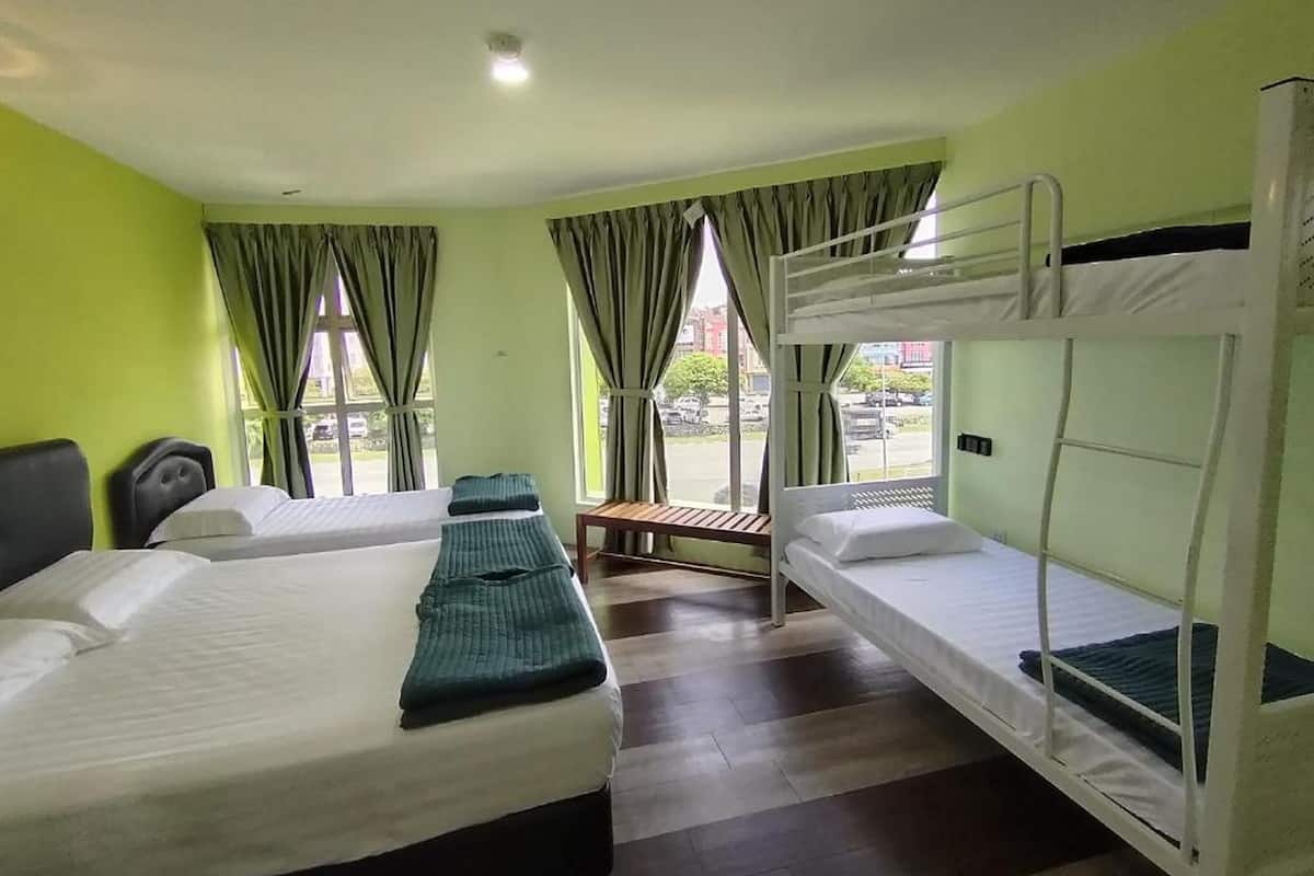 A hotel room with two beds, a bench, and a window with curtains.