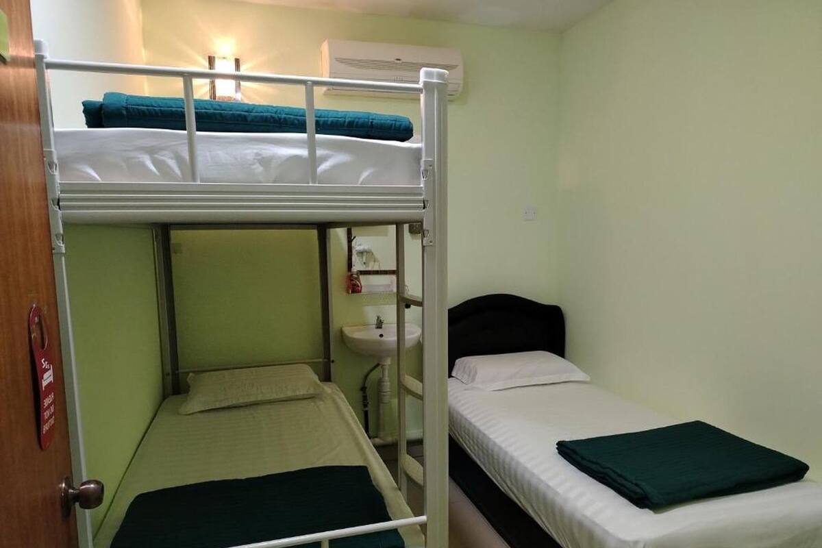 Une chambre avec un lit superposé, un lavabo et une fenêtre.