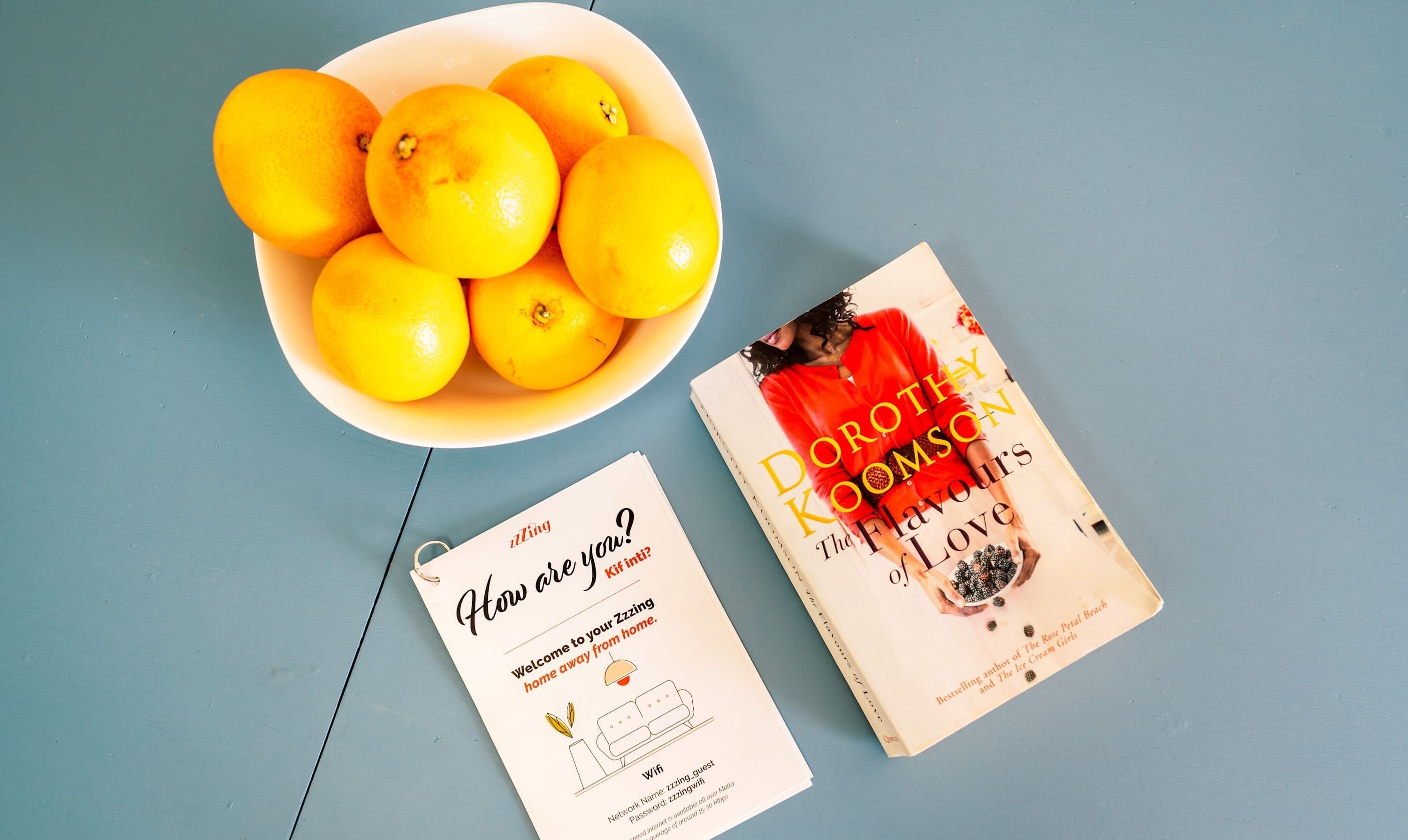 Un cuenco de limones, un libro titulado 'The Flavours of Love' de Dorothy Koomson, y un cartel de Wi-Fi.