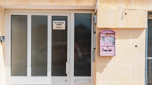 L’entrée d’un immeuble, avec une plaque indiquant : « TAL-MIELHA COURT, BÂTIMENT B ».