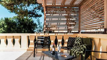 Ein Sitzbereich im Freien mit einer Pergola, Stühlen, einem Tisch und einer Weinflasche.