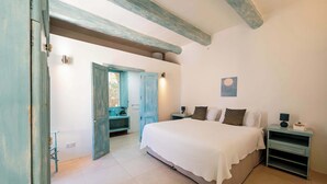 Un dormitorio con cama, mesita de noche, cómoda, ventana y puerta.