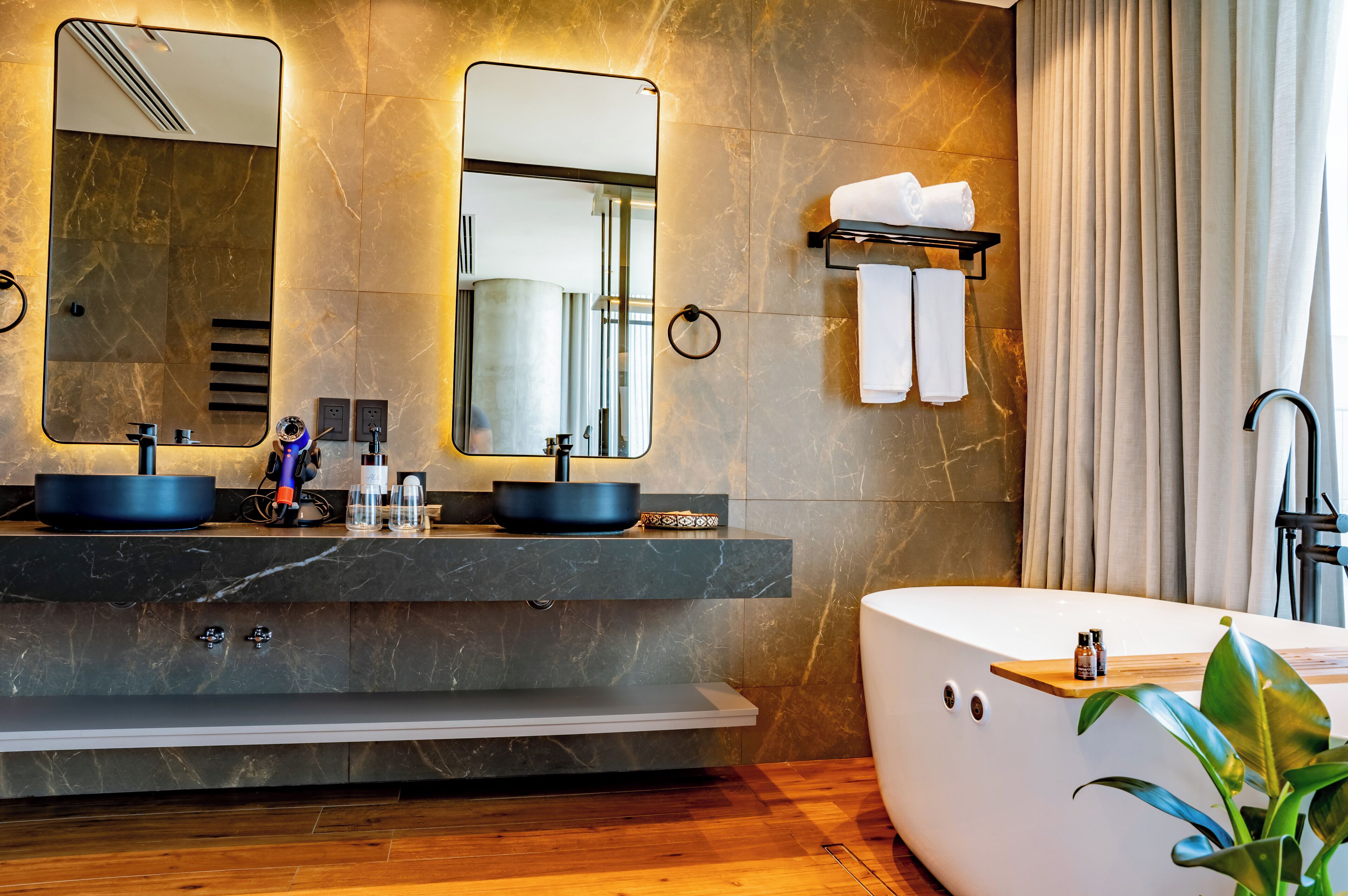 A modern bathroom with two sinks, a large bathtub, and a mirror.