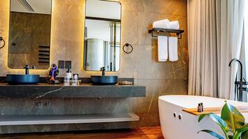 A modern bathroom with two sinks, a large bathtub, and a mirror.