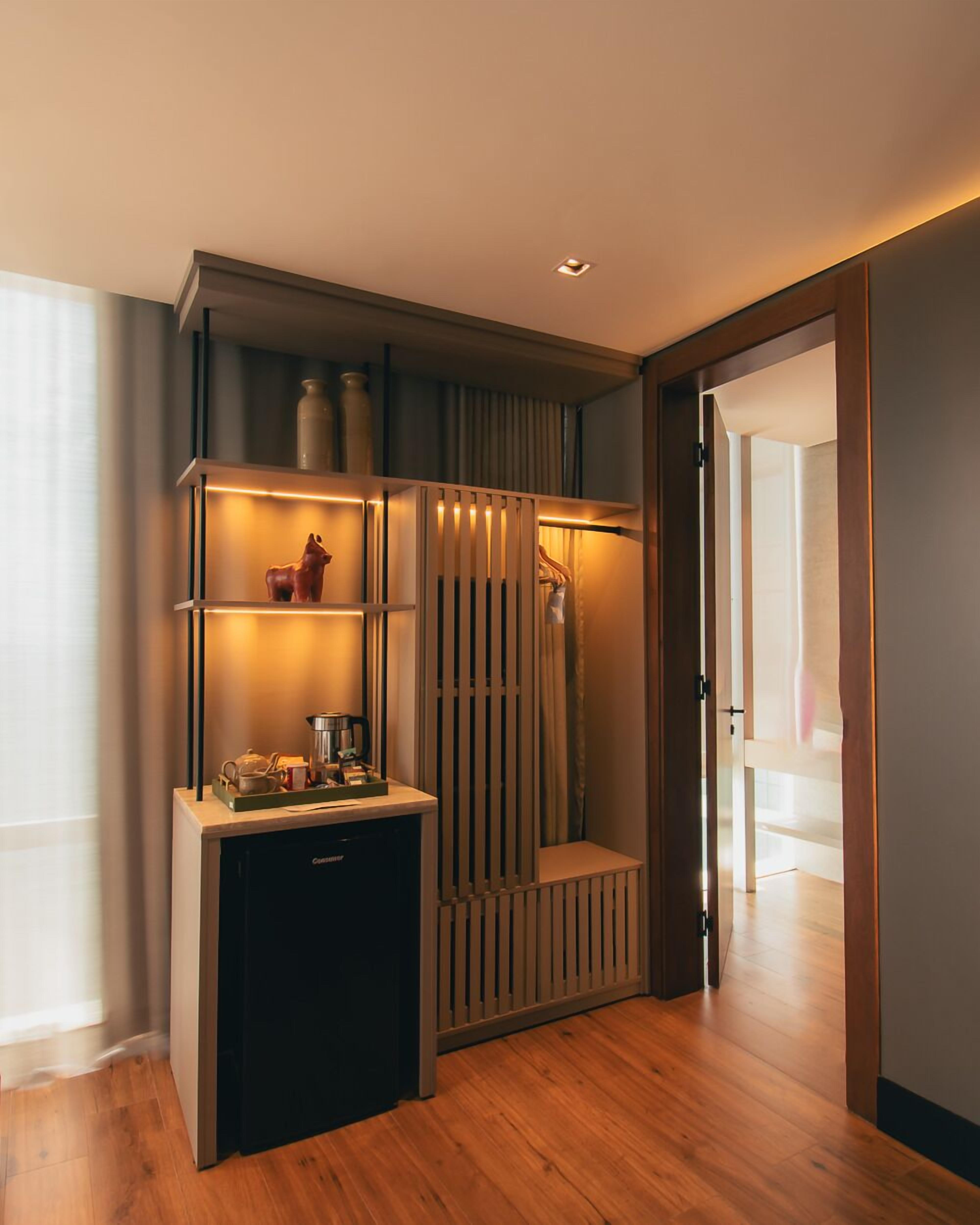 A modern room with a built-in kitchen area, a seating bench, and a door leading to another space.