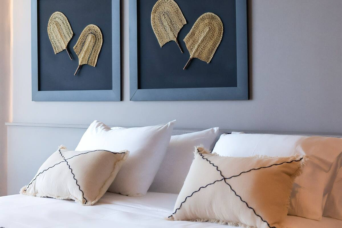 A neatly made bed with patterned pillows and a geometric throw blanket.