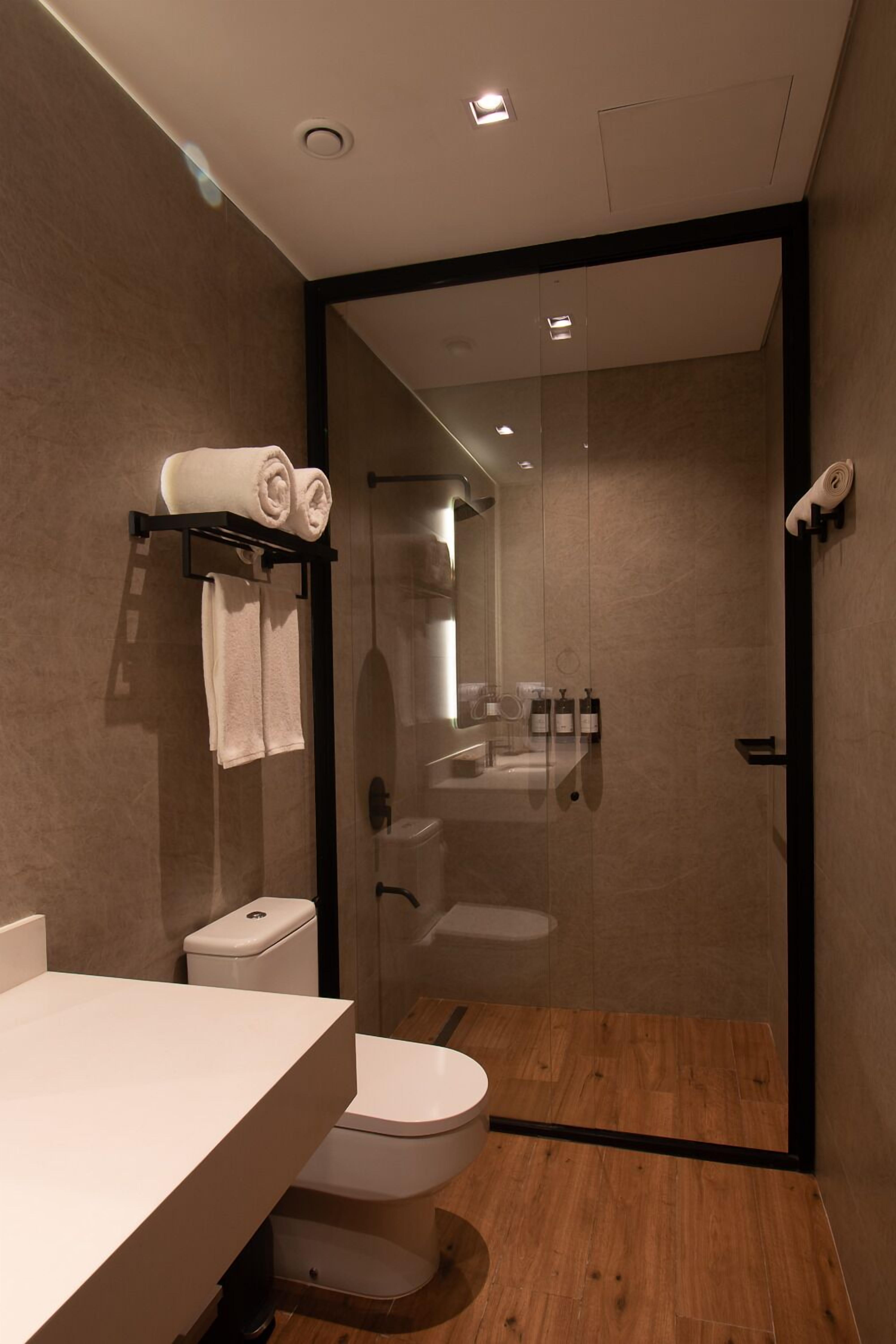 Un bagno moderno con box doccia in vetro, un water e un lavandino.