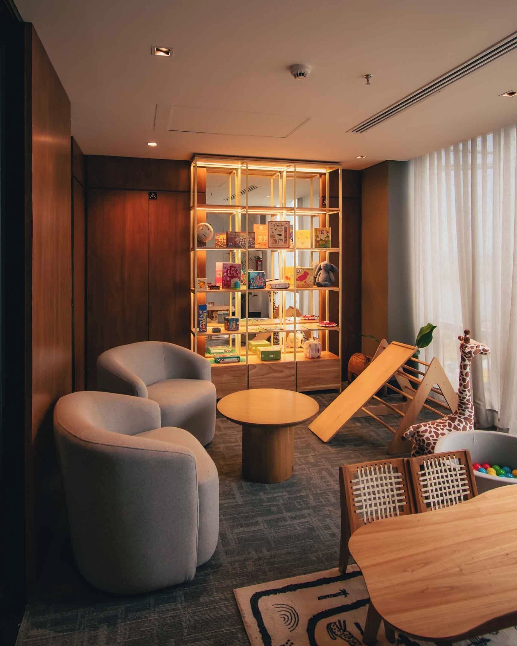 A modern room with a bookshelf, two armchairs, a round table, and a giraffe decoration.