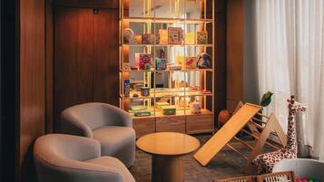 Una habitación moderna con una estantería, dos sillones, una mesa redonda y una decoración con un girafa.