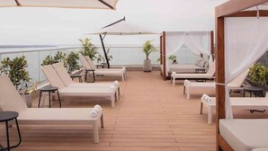 A rooftop lounge with sunbeds and umbrellas, overlooking a body of water. - Alula Hotel Encarnacion (Encarnación)
