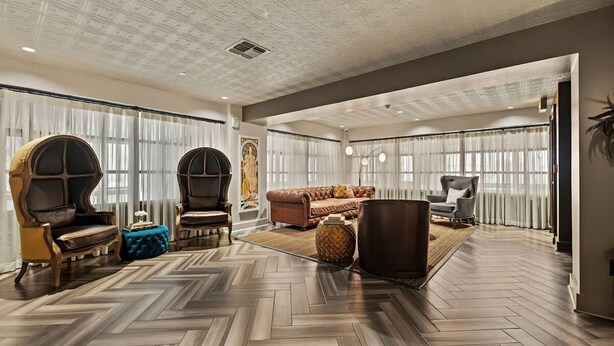 A spacious living room with a herringbone floor, large windows with sheer curtains, and a mix of modern and classic furniture. - Modern Urban Retreat Steps from River Walk | Ideal for City Lovers & Explorers (San Antonio)