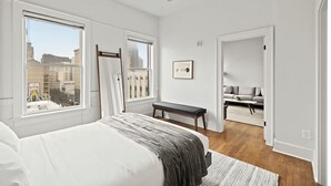Ein Schlafzimmer mit einem großen Bett, einem Deckenventilator und Blick auf die Stadt durch das Fenster.