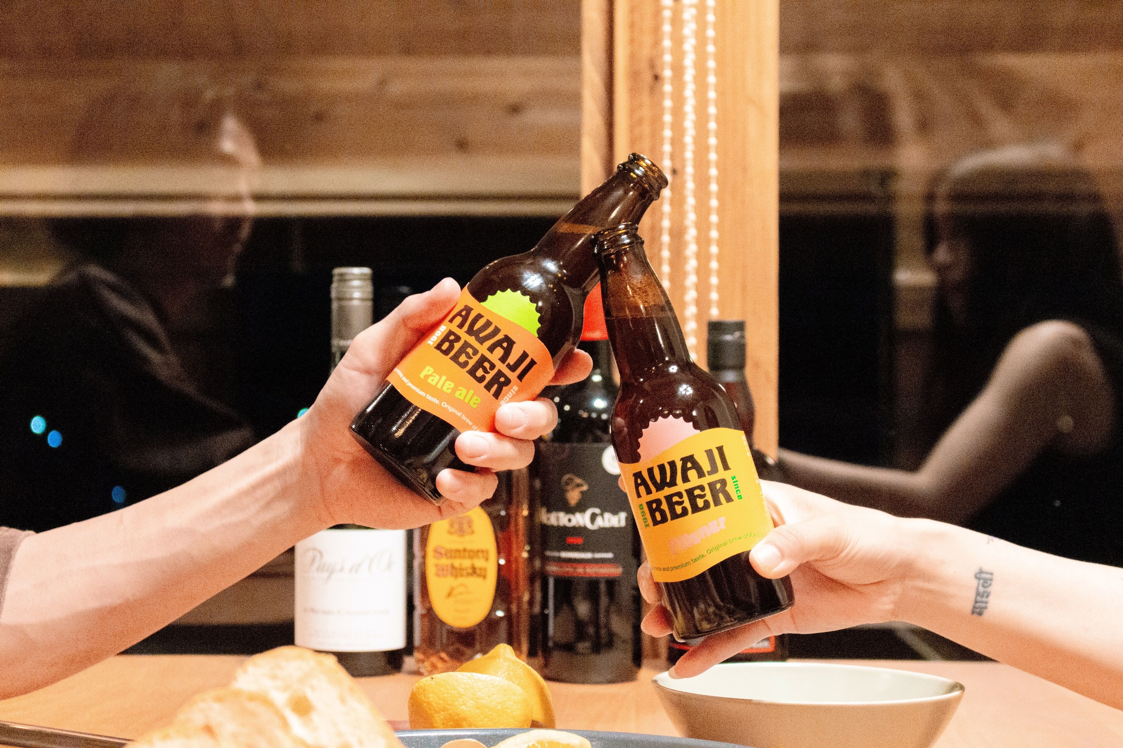 Due persone che tengono in mano bottiglie di Awaji Beer.