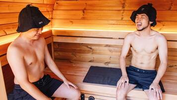Dos hombres sentados en una sauna con paredes y bancos de madera.