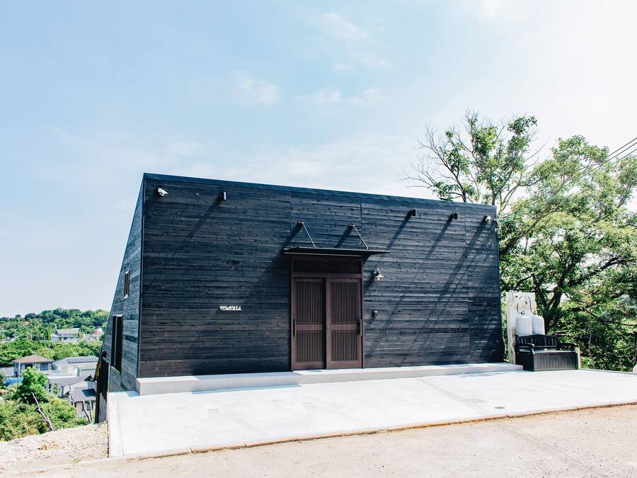 A modern building with a dark facade, a central entrance, and a flat roof.