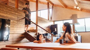 A modern interior with wooden beams, a staircase, and a kitchen area. - Villa SCALA (Sumoto)