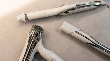 Een witte elektrische tandenborstel en een witte haardroger op een beige oppervlak.