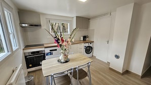 Una cocina compacta con mesa, sillas, lavadora y radiador.