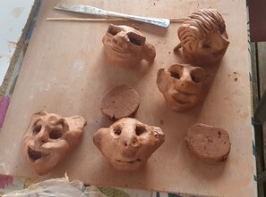 A clay sculpture with a sculpting tool on a work surface.