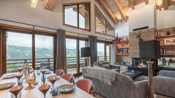A spacious living area with a fireplace, large windows, and a view of the mountains.