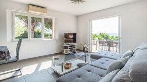 A modern living room with a sofa, TV, and a glass coffee table. There is a balcony with a view of the sea. - Awesome home in Roquebrune-sur-Argens with WiFi (Roquebrune-sur-Argens)