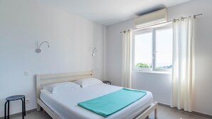 A bedroom with a bed, a window with curtains, a wall-mounted air conditioner, and a small stool. - Awesome home in Roquebrune-sur-Argens with WiFi (Roquebrune-sur-Argens)