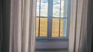 Una finestra con vista su un campo, oltre una tenda.