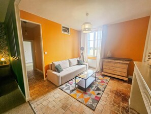 Una sala de estar con sofá, mesa de centro, cómoda y ventana con cortinas.