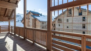 A wooden deck with a view of snow-covered buildings and mountains. - Exceptional apartment, ski-in, sauna, parking included (Méribel)
