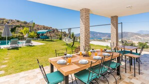 A dining area with a table set for six, outdoor chairs, and a view of the landscape.