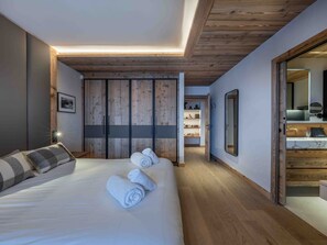A bedroom with a large bed, wooden wardrobe, and a walk-in closet.