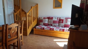 Una habitación con una cama de madera, un escritorio, una silla, una escalera de madera y un espejo en la pared.