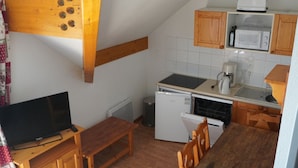 Una cocina compacta con armarios de madera, microondas, cafetera y lavavajillas.