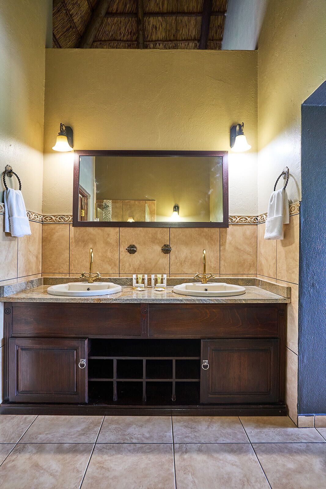 A bathroom with a double sink vanity, a large mirror, and two wall-mounted lights.