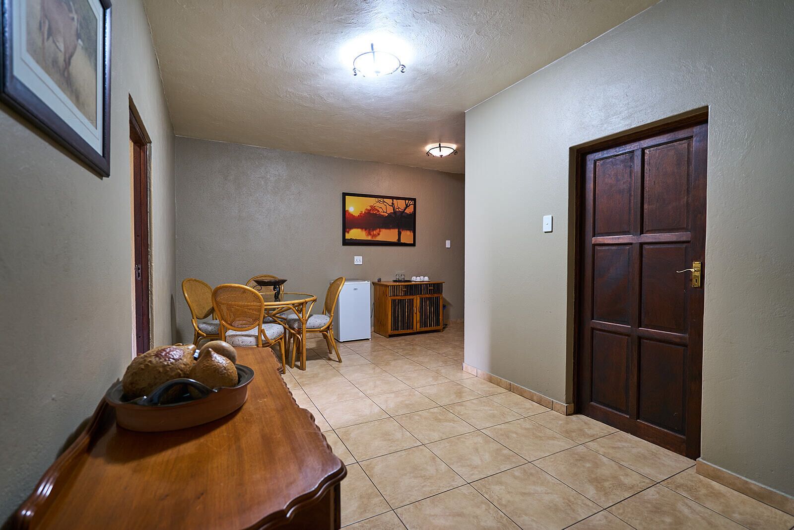 A hallway with a dining area, a refrigerator, and a door.