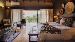 A hotel room with a bed, a chair, a table, a lamp, and a view through the window. - Sable Ranch Thaba Khaya (Brits)