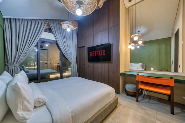 A modern hotel room with a large bed, a TV mounted on the wall, a desk with a chair, and a large mirror.