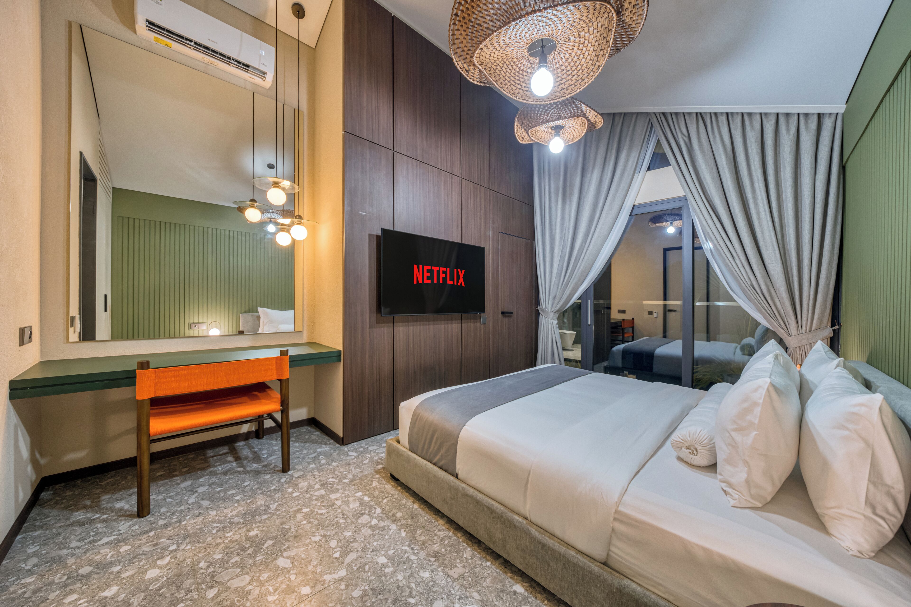 A hotel room with a bed, a bench, a TV, and a mirror.