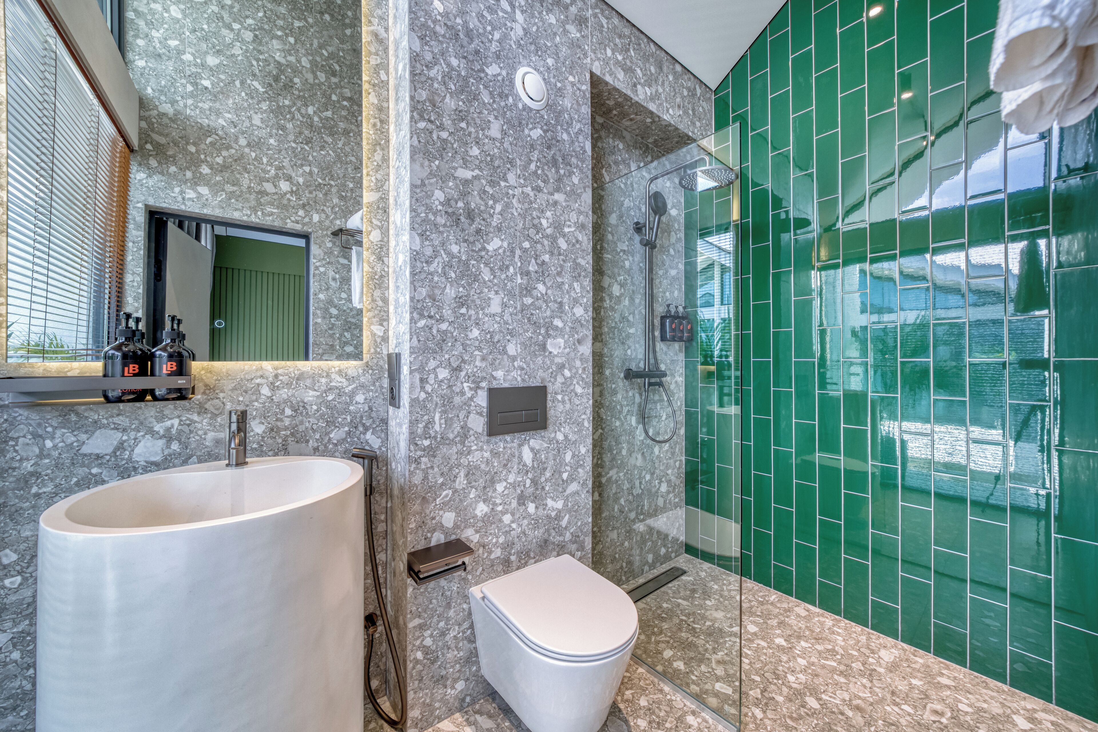 A modern bathroom with a marble sink, toilet, and a glass-enclosed shower area.