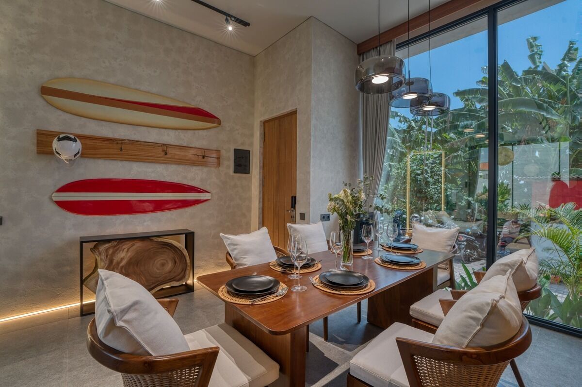 A dining area with a table set for four, surrounded by wicker chairs with white cushions.