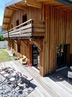 A wooden cabin with a deck, outdoor seating, and a large sliding glass door. - Refugium Draudes with mountain view (Les Houches)