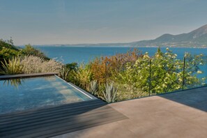 A modern infinity pool with a clear view of the sea and distant mountains. - Secluded villa, epic views, pool & sauna - 6 mins drive from town centre and pubic beach. (Brenzone sul Garda)