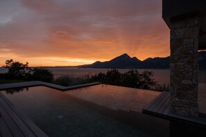 A infinity pool with a view of mountains and a body of water at sunset. - Secluded villa, epic views, pool & sauna - 6 mins drive from town centre and pubic beach. (Brenzone sul Garda)