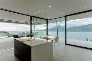 A modern office space with a large desk, chairs, and a view of a lake and mountains. - Secluded villa, epic views, pool & sauna - 6 mins drive from town centre and pubic beach. (Brenzone sul Garda)