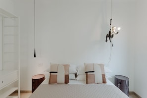 A minimalist bedroom with a bed, bedside tables, and a hanging light fixture. - Secluded villa, epic views, pool & sauna - 6 mins drive from town centre and pubic beach. (Brenzone sul Garda)