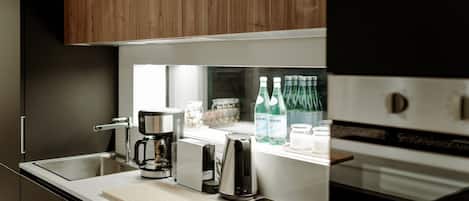 A modern kitchen with a built-in coffee maker, a toaster, and a refrigerator.