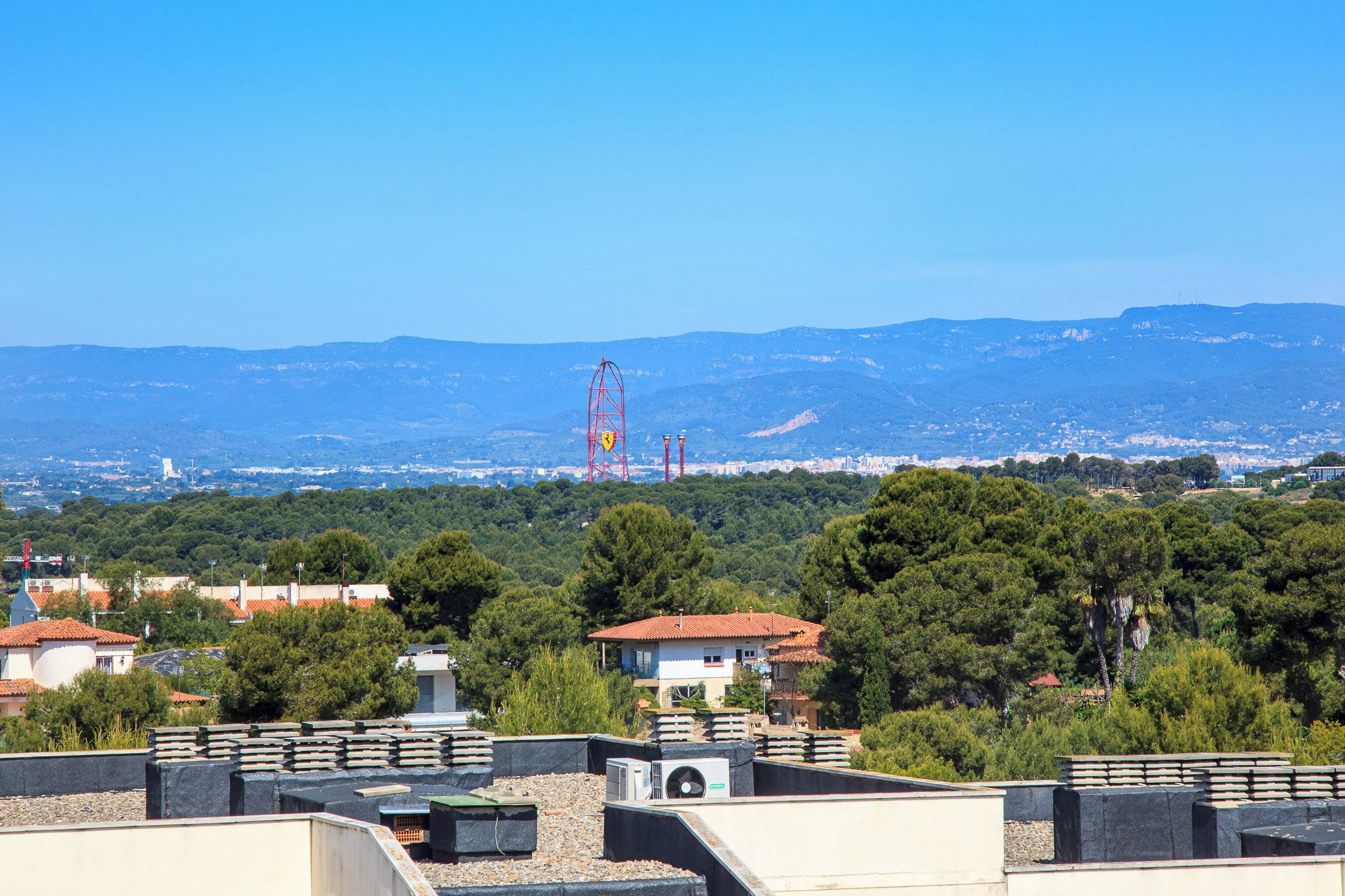 A residential area with houses, trees, and distant mountains.
