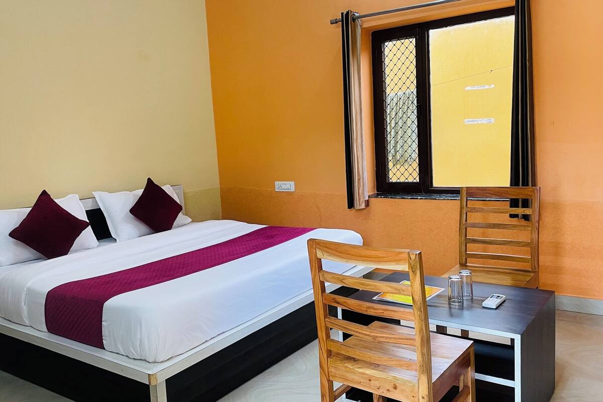 A hotel room with a bed, a desk, and a chair.