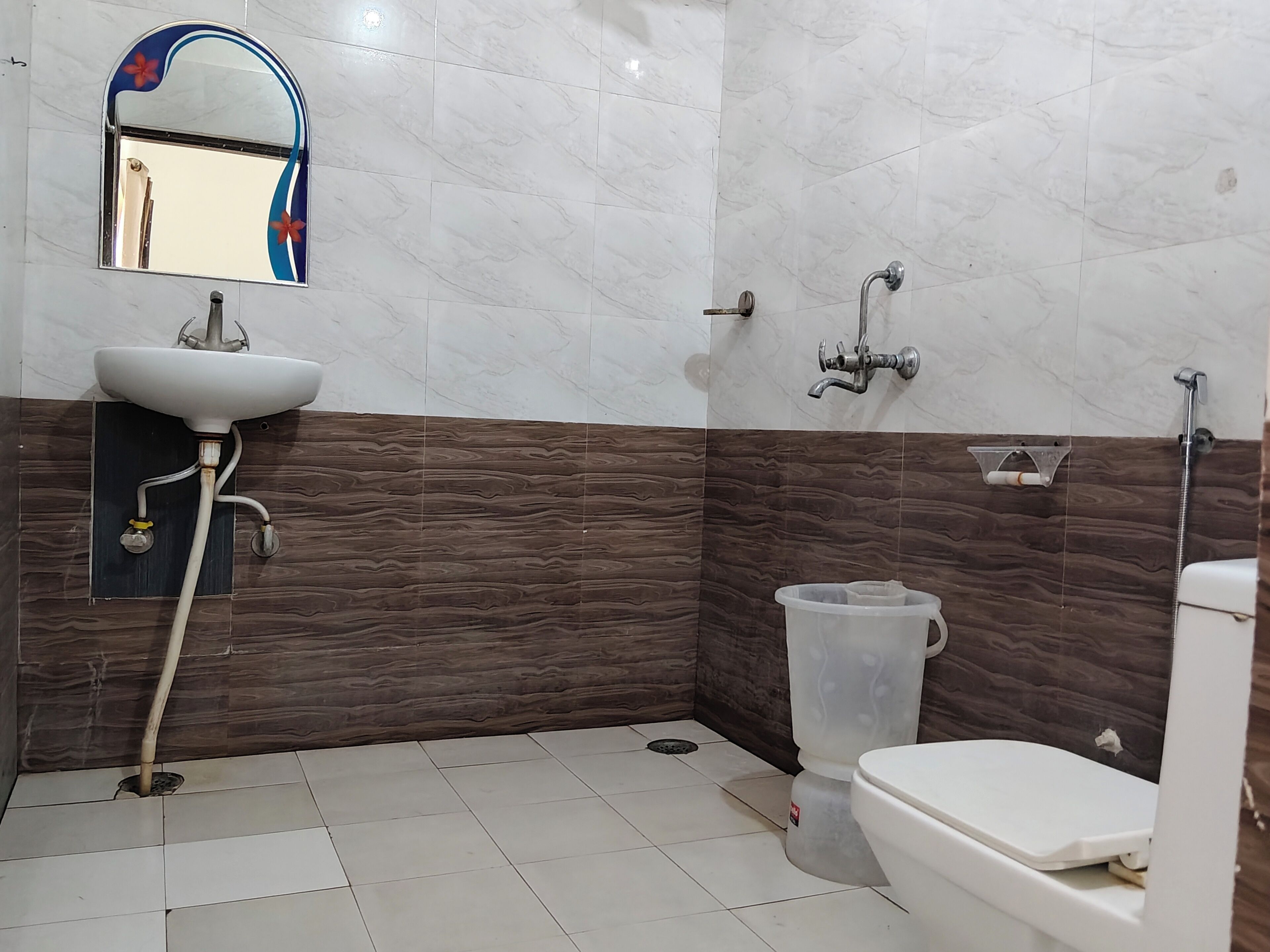 A bathroom with a sink, toilet, shower, and a mirror with a decorative frame.