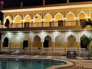 A hotel with a pool, outdoor seating, and traditional architectural arches.